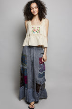 Woman wearing a floral top and patchwork skirt on a gray background