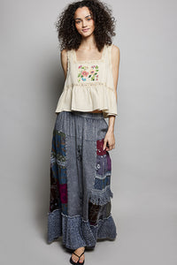 Woman wearing a floral top and patchwork skirt on a gray background