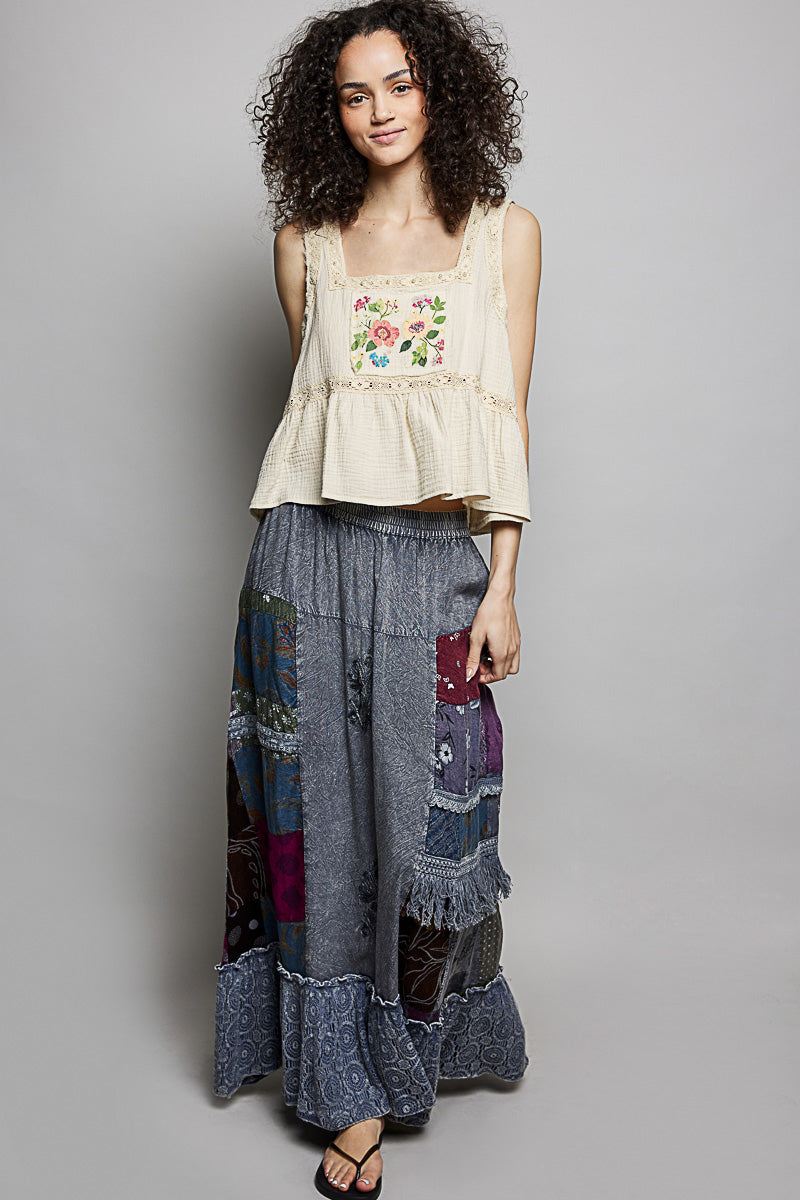 Woman wearing a floral top and patchwork skirt on a gray background