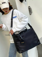 Person holding a black bag with visible branding, wearing a white sweatshirt and cap.