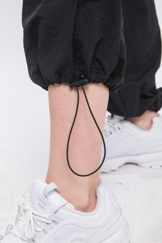A close up of how pull drawstring at the bottom of Loose Fit Parachute Cargo Pants-black