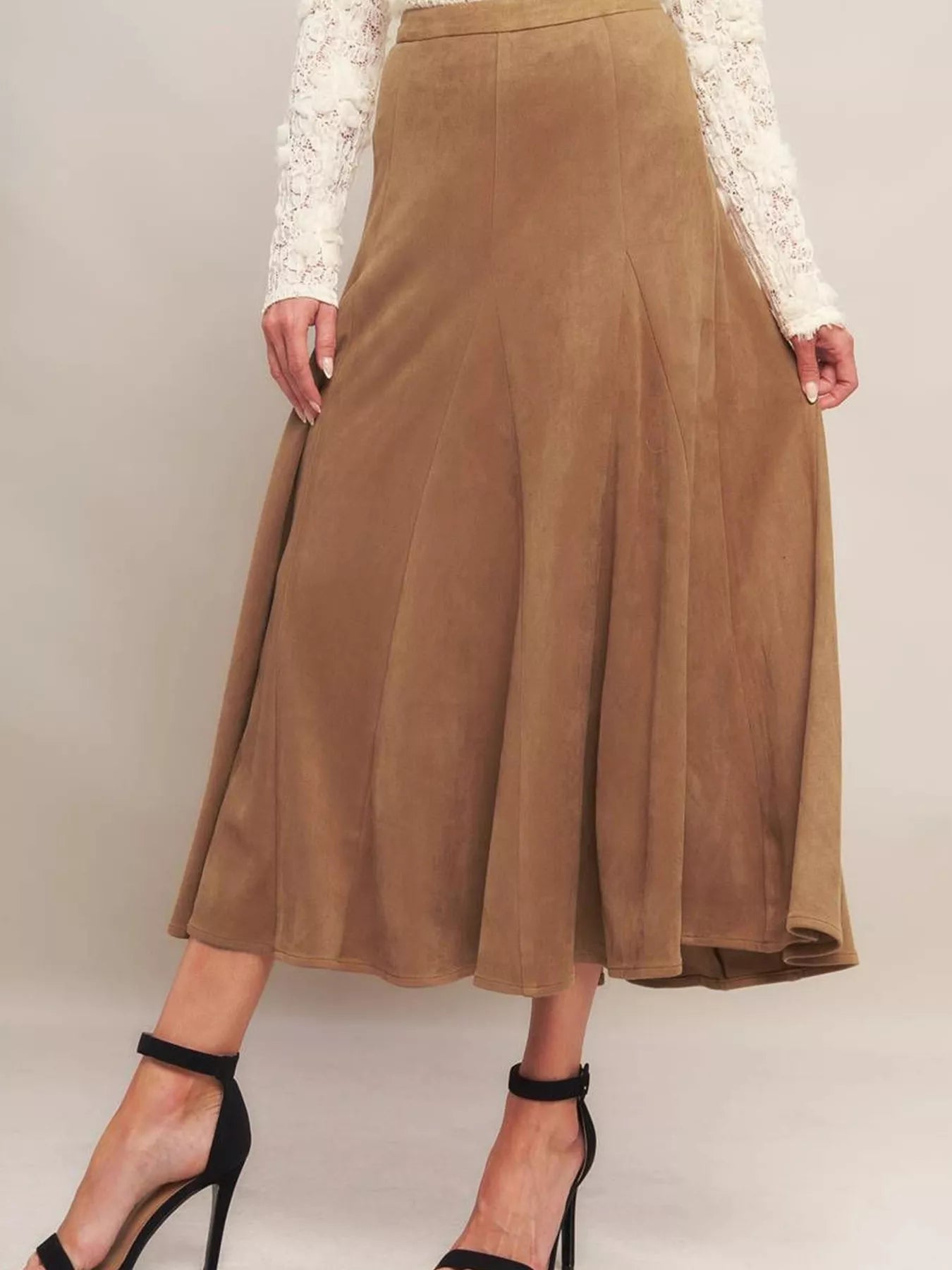 Brown suede skirt worn by a person on a plain background