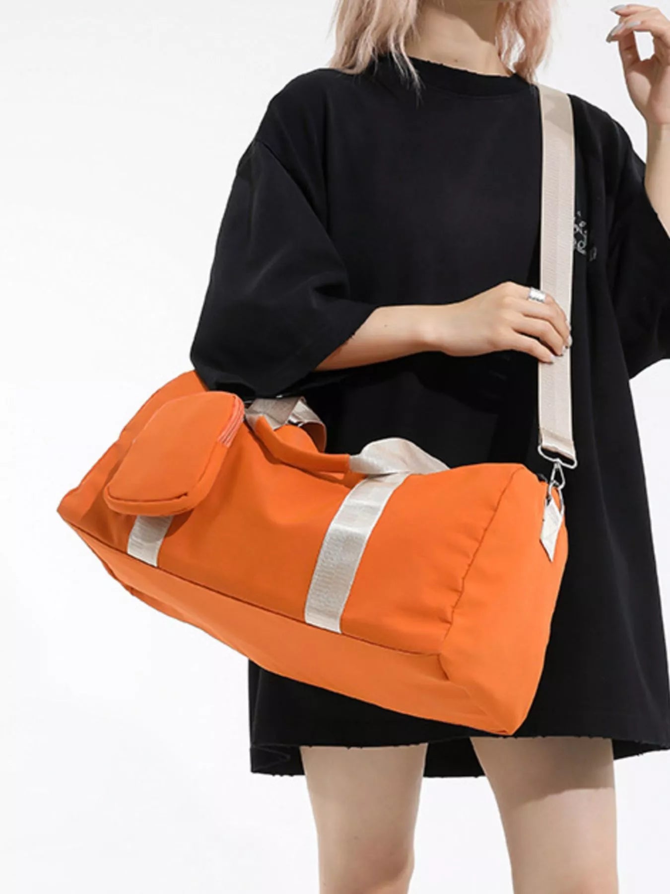 Person holding an orange duffel bag with a white background