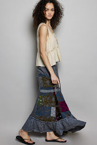 Woman wearing a long, patterned skirt against a plain background