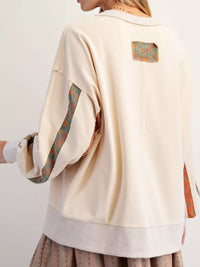 Beige jacket with patterned sleeves and back patch on a plain background