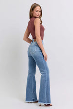 Woman wearing a brown top and blue flared jeans on a white background