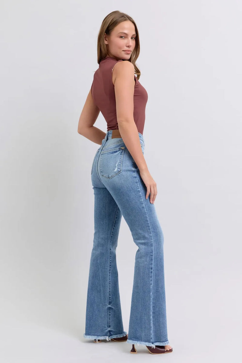 Woman wearing a brown top and blue flared jeans on a white background