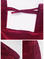 Close-up of a red velvet garment with a bow detail on a white background.