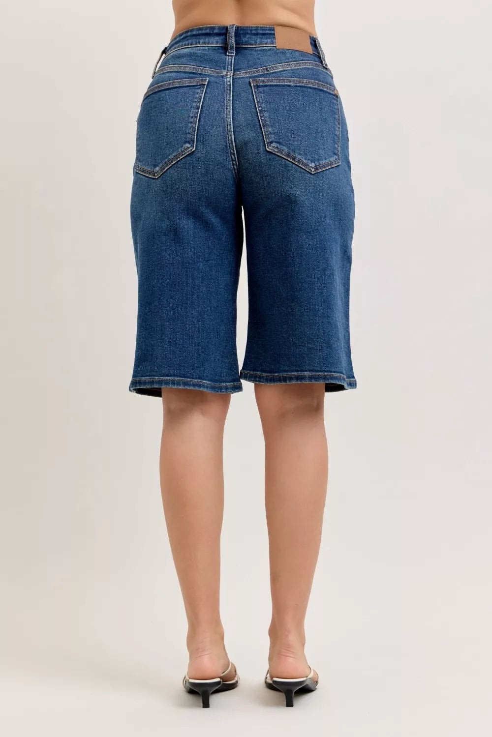 Person wearing blue denim shorts on a plain background