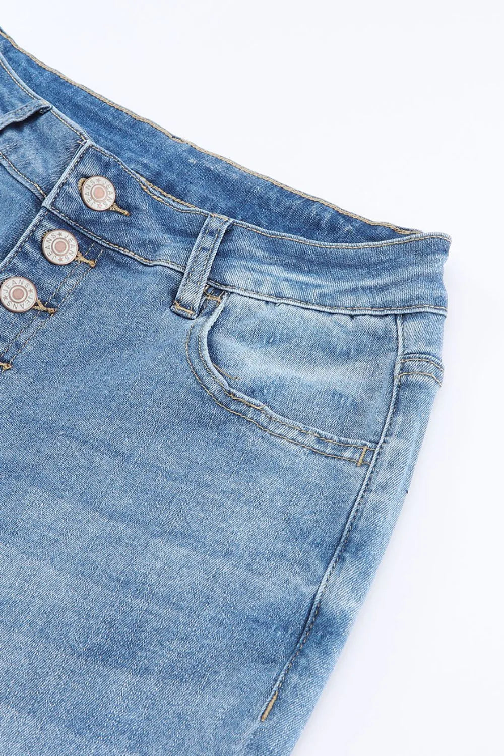 Close-up of blue denim jeans with buttons on a white background