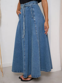 Long denim skirt worn by a person on a plain background