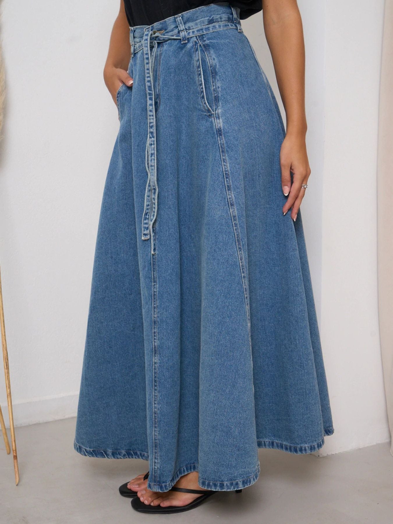 Long denim skirt worn by a person on a plain background