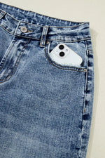 Close-up of blue denim jeans with a phone in the pocket on a beige background