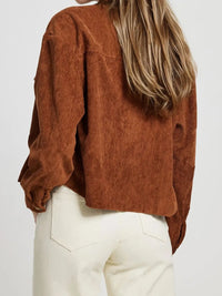 Person wearing a brown corduroy shirt and white pants on a plain background