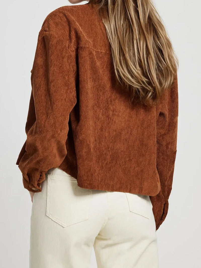 Person wearing a brown corduroy shirt and white pants on a plain background