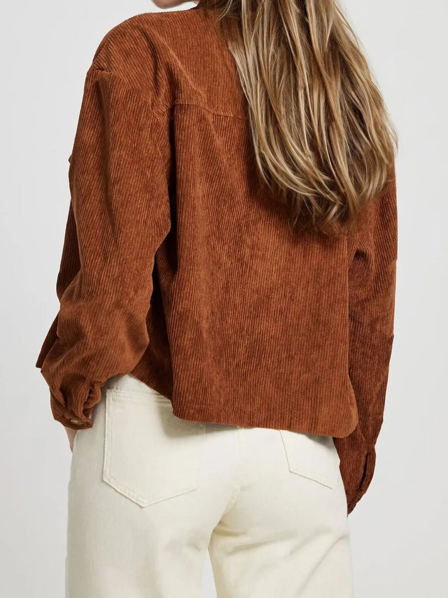 Person wearing a brown corduroy shirt and white pants on a plain background