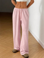 Person wearing pink pajama pants standing on a wooden floor.