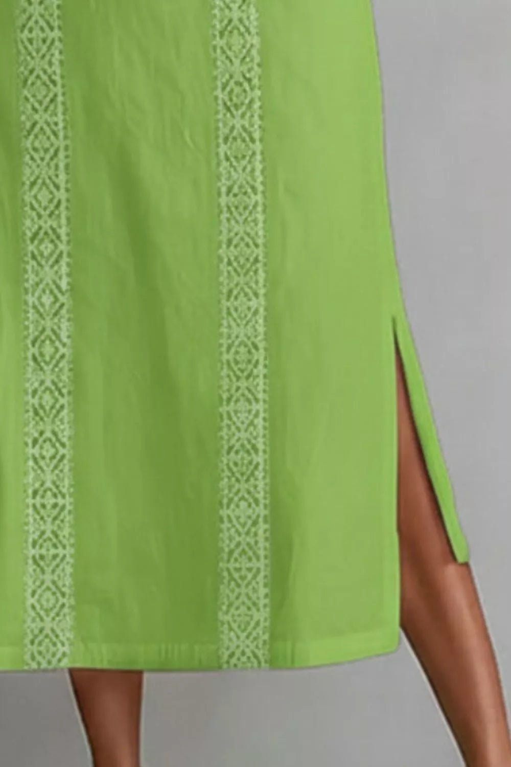 Green dress with white lace detailing on a gray background