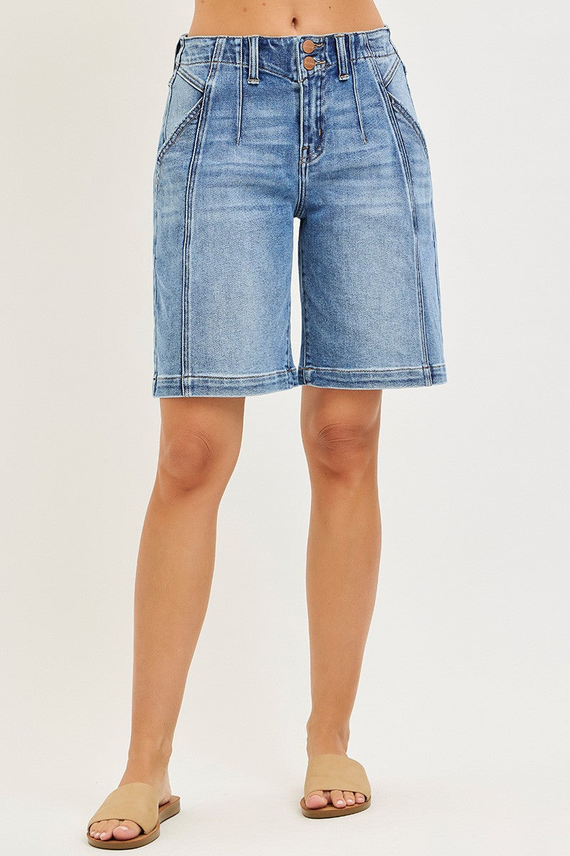 Denim shorts worn by a person on a plain background