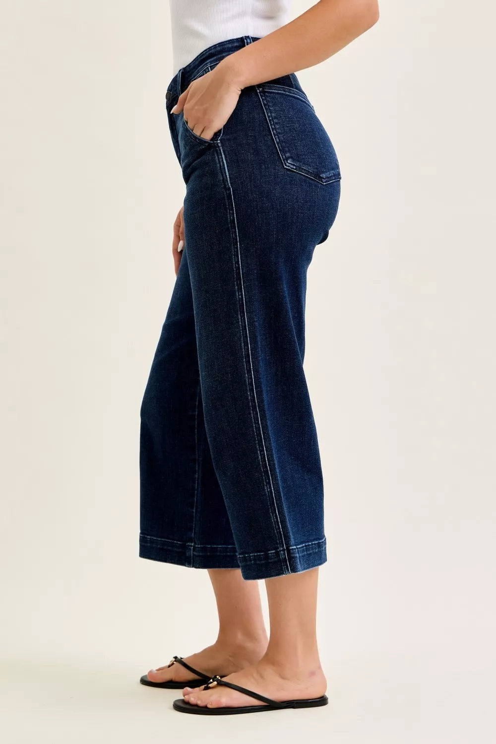 Person wearing blue jeans on a plain background