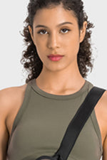 Woman wearing a green tank top with a black strap over her shoulder on a white background