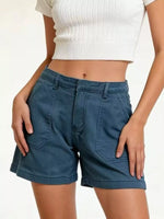 Person wearing blue shorts and a white top on a plain background