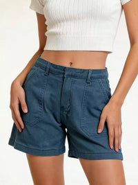 Person wearing blue shorts and a white top on a plain background