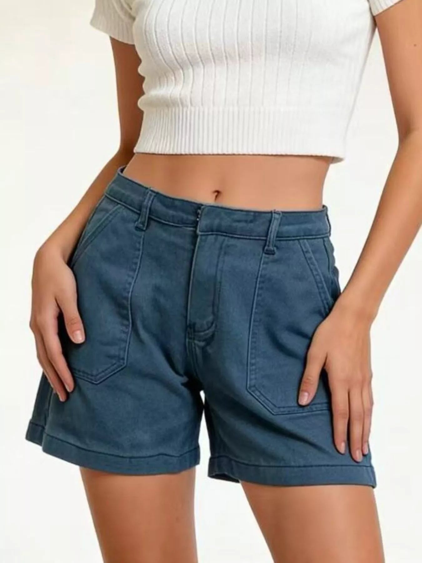 Person wearing blue shorts and a white top on a plain background