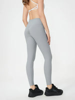 Person wearing gray leggings and black sneakers on a white background