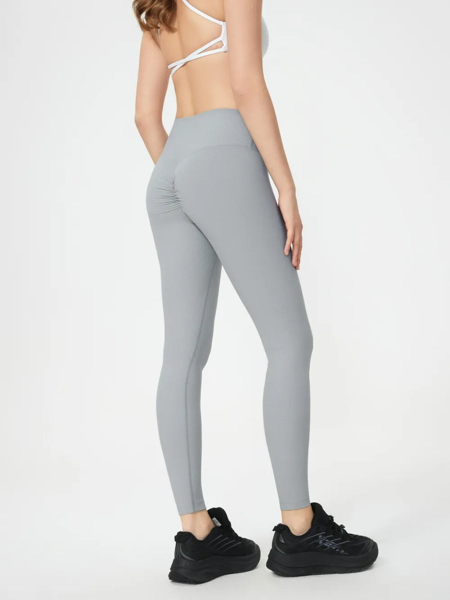 Person wearing gray leggings and black sneakers on a white background