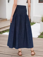 Person wearing a blue denim skirt standing on a wooden deck.