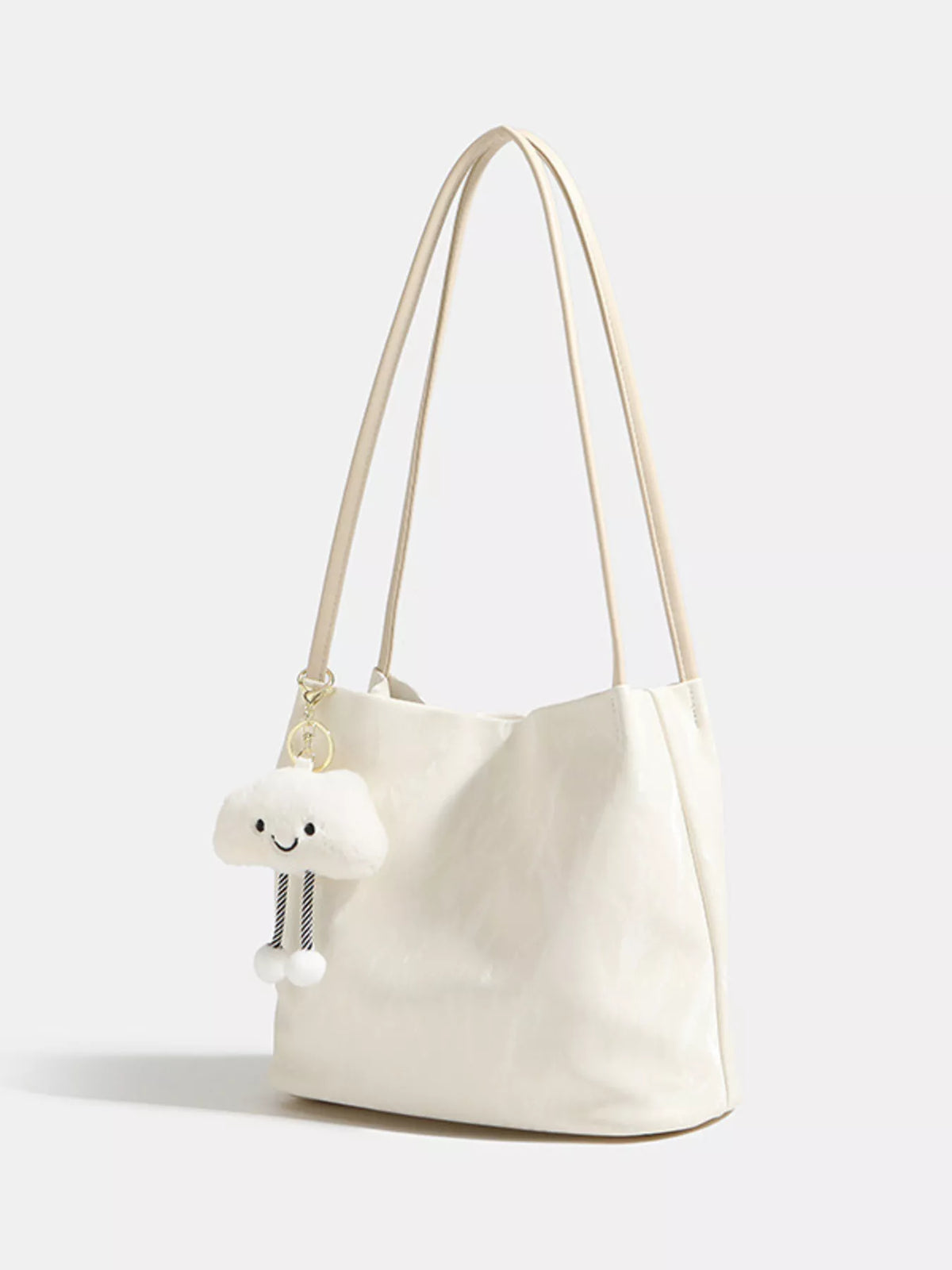 White handbag with a small white plush toy attached to it on a light gray background