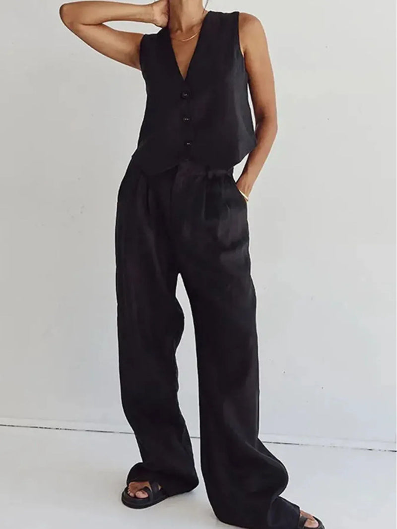 Person wearing a black sleeveless top and wide-leg pants on a white background