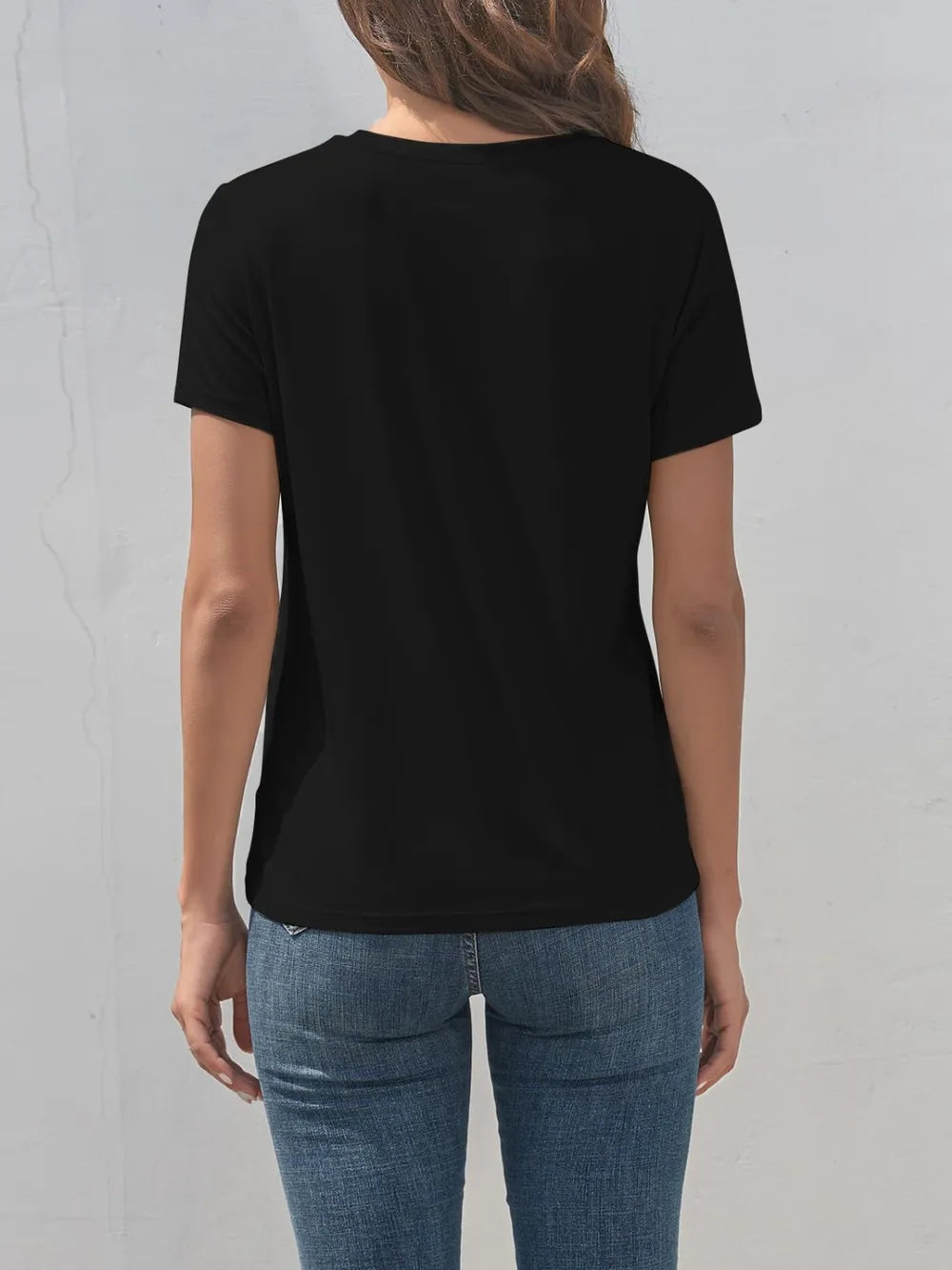 Person wearing a black t-shirt and blue jeans against a gray background