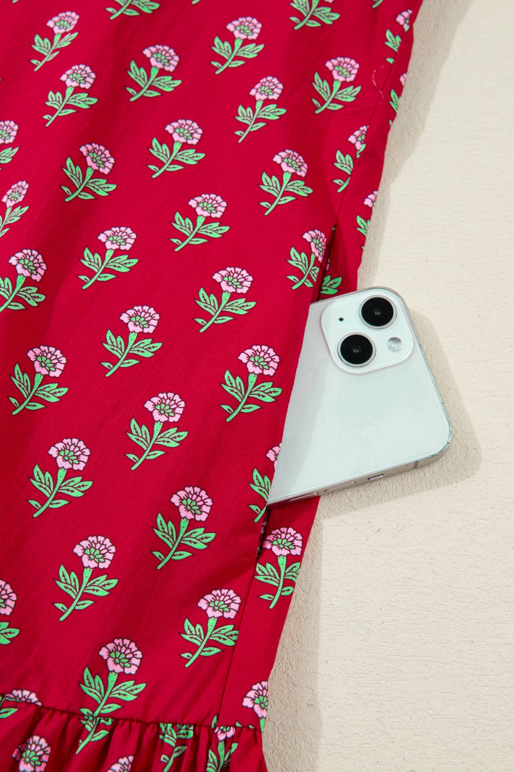 Red fabric with floral pattern holding a smartphone on a beige surface