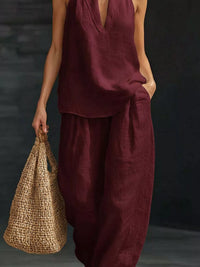 Person wearing a burgundy outfit holding a woven bag against a dark background