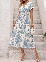 Woman in a blue and white floral dress standing on stone steps.