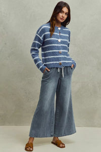 Woman wearing a blue striped sweater and jeans against a neutral background