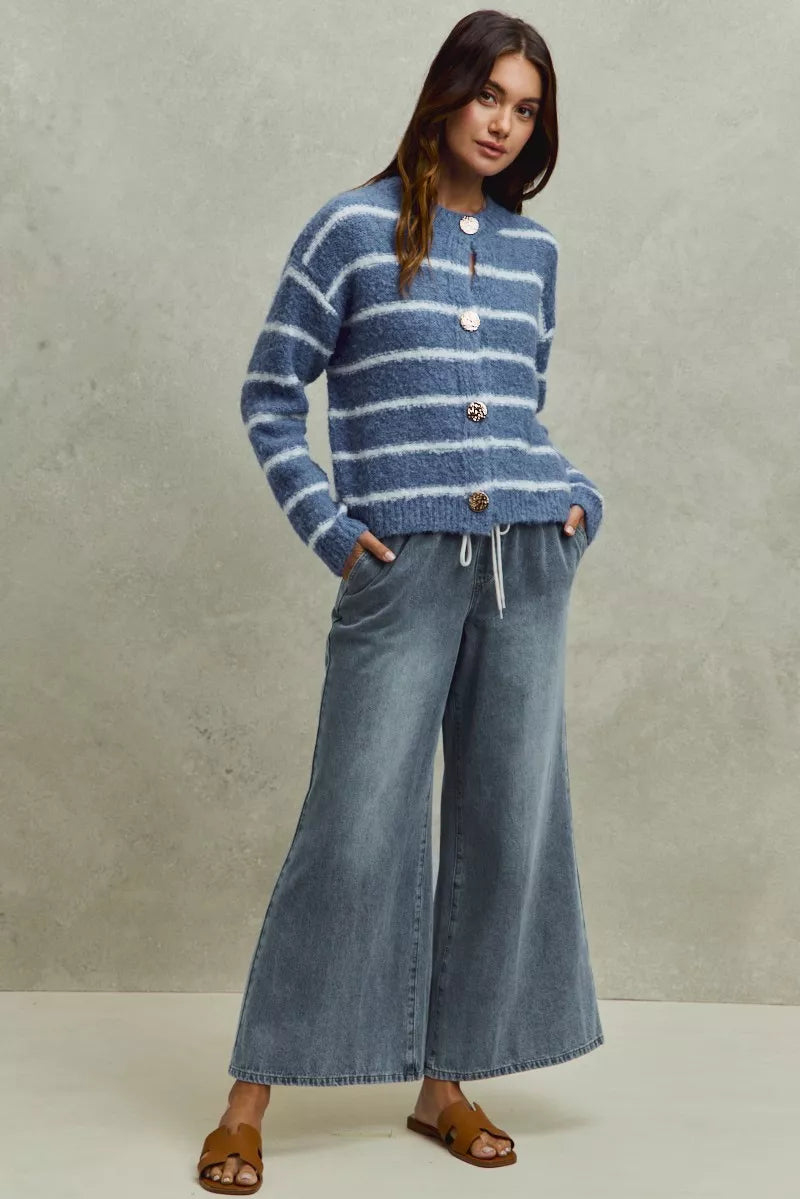 Woman wearing a blue striped sweater and jeans against a neutral background