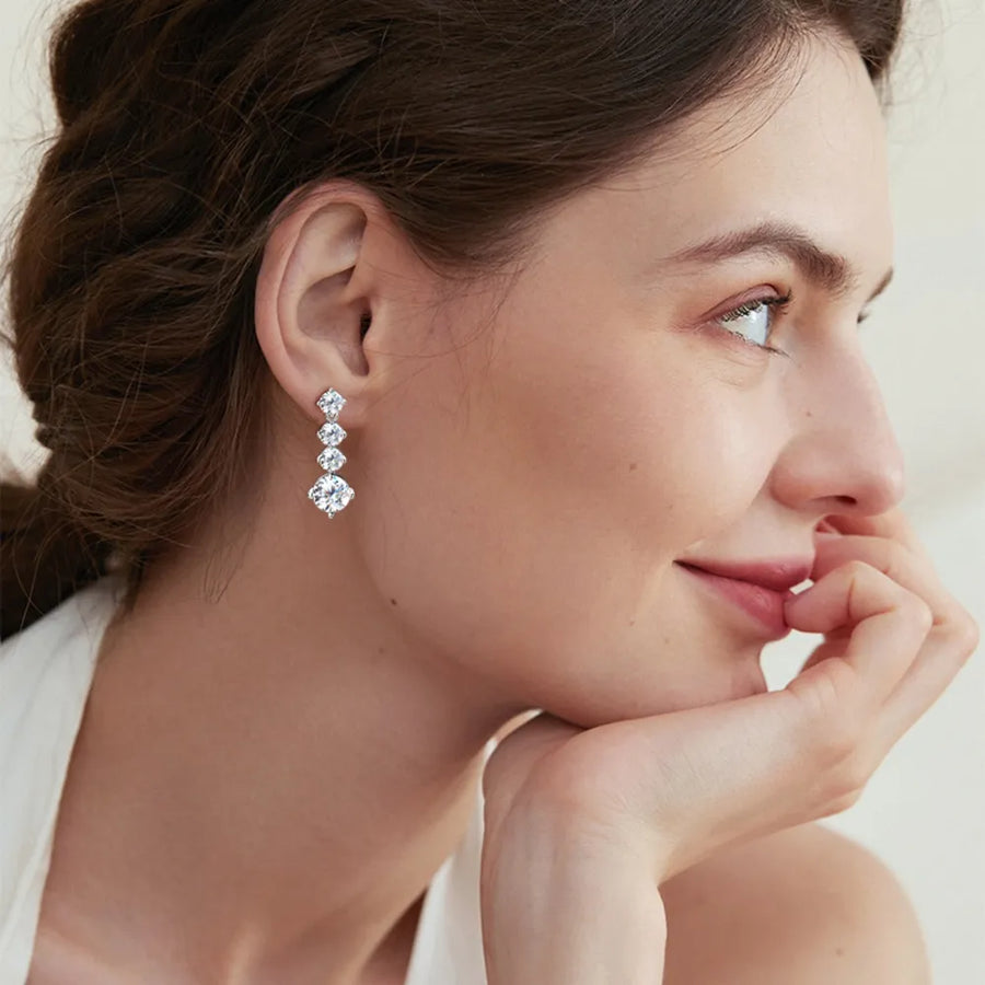 Woman wearing a set of diamond earrings with a soft background