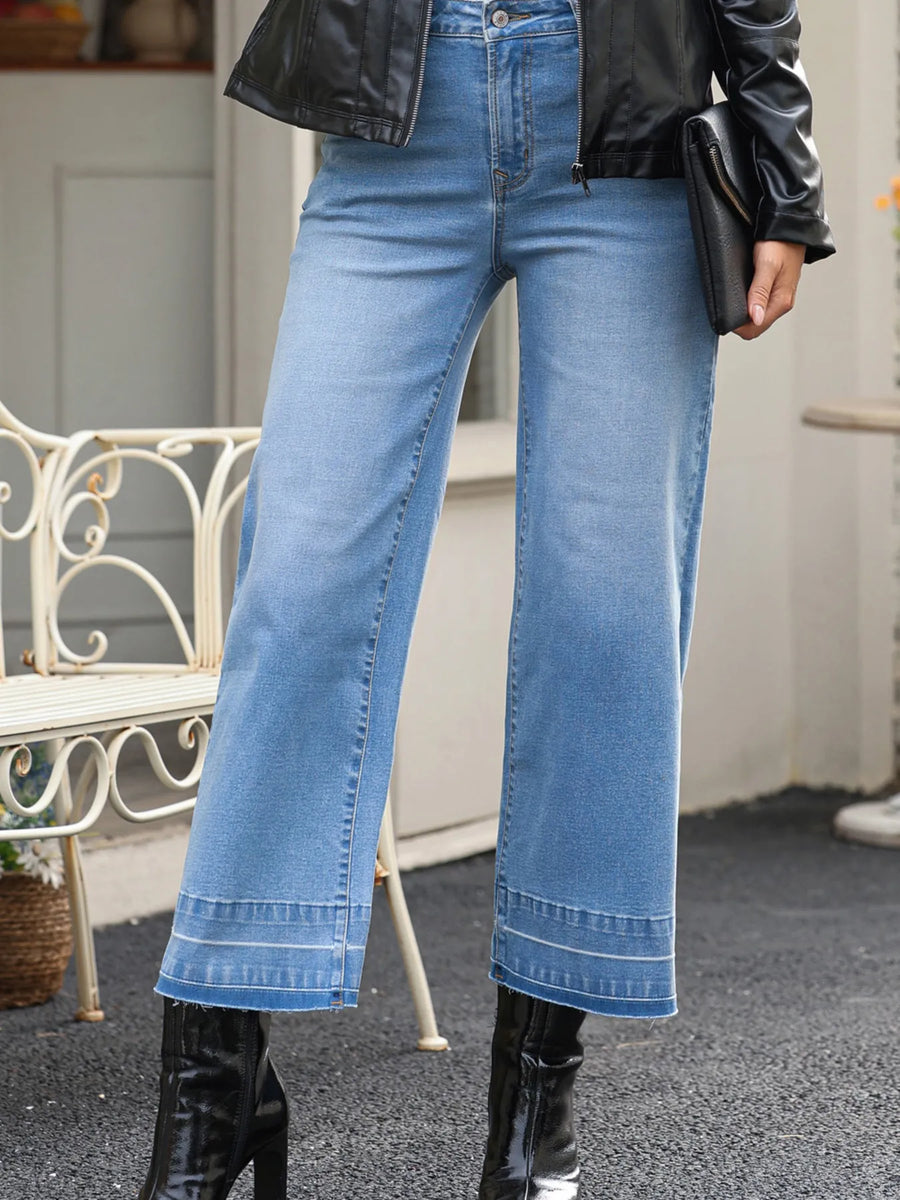 Person wearing blue jeans and black leather jacket with blurred background