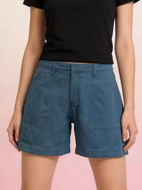 Person wearing blue shorts and a black top on a pink background