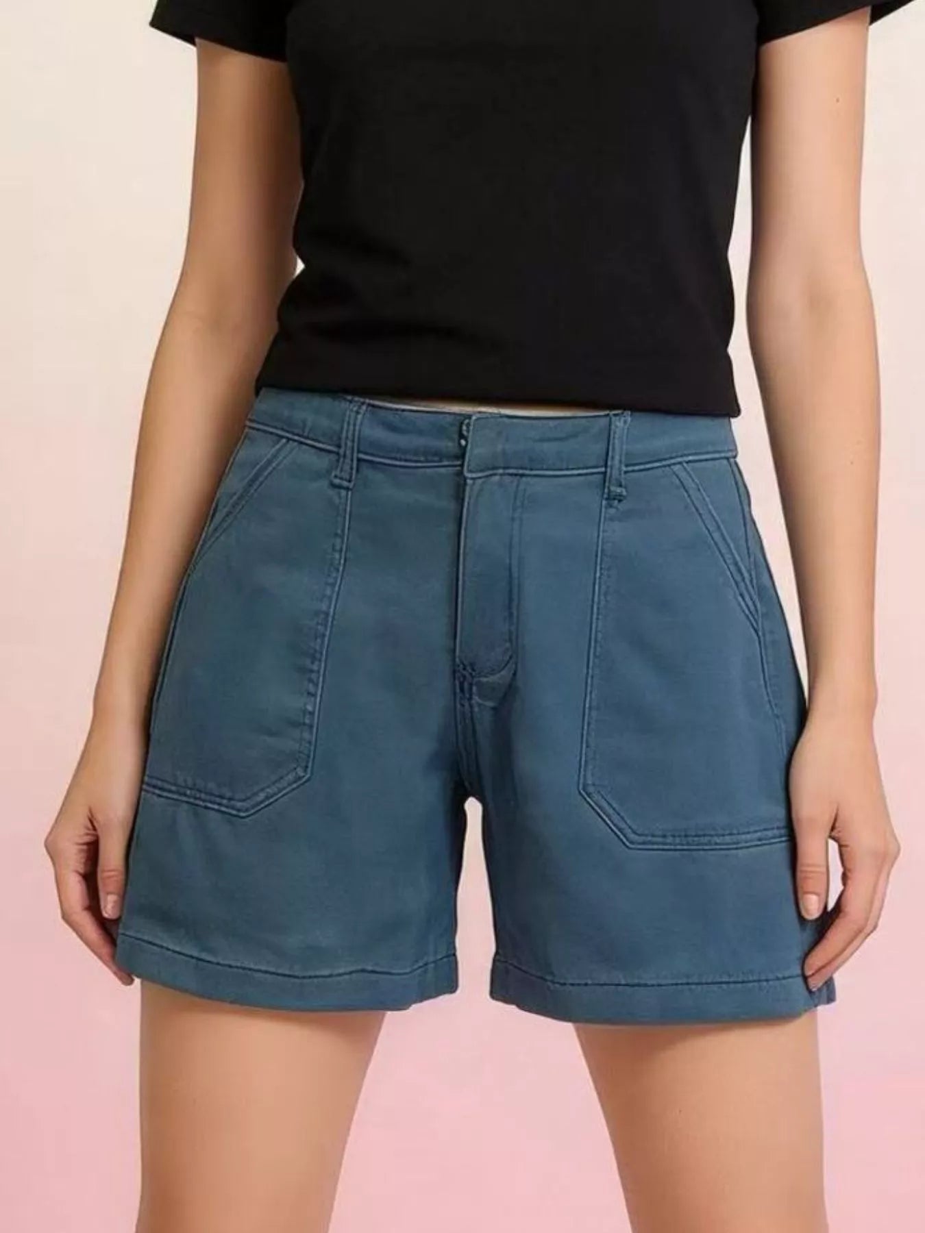 Person wearing blue shorts and a black top on a pink background