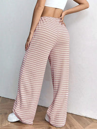 Person wearing pink checkered pants with a white background