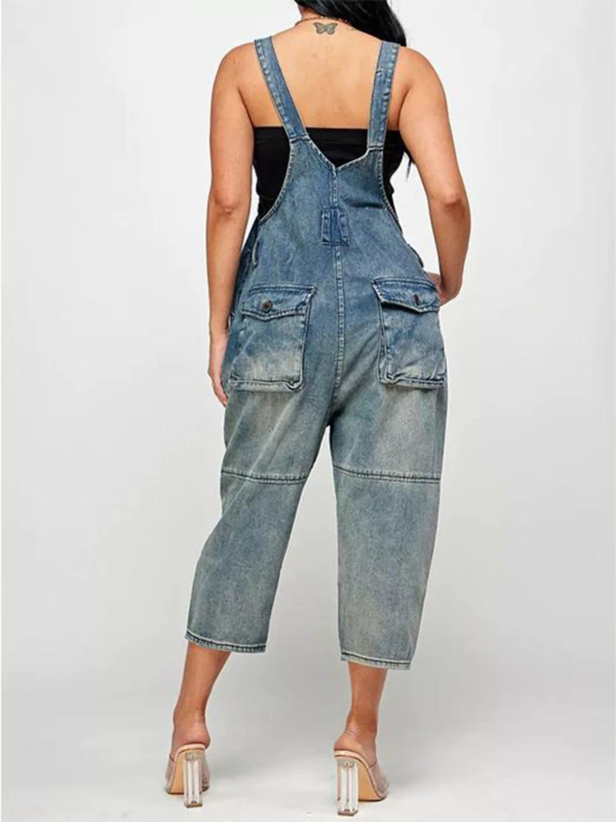 Person wearing blue denim overalls on a white background