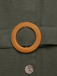 Close-up of a woven belt buckle on a green fabric background