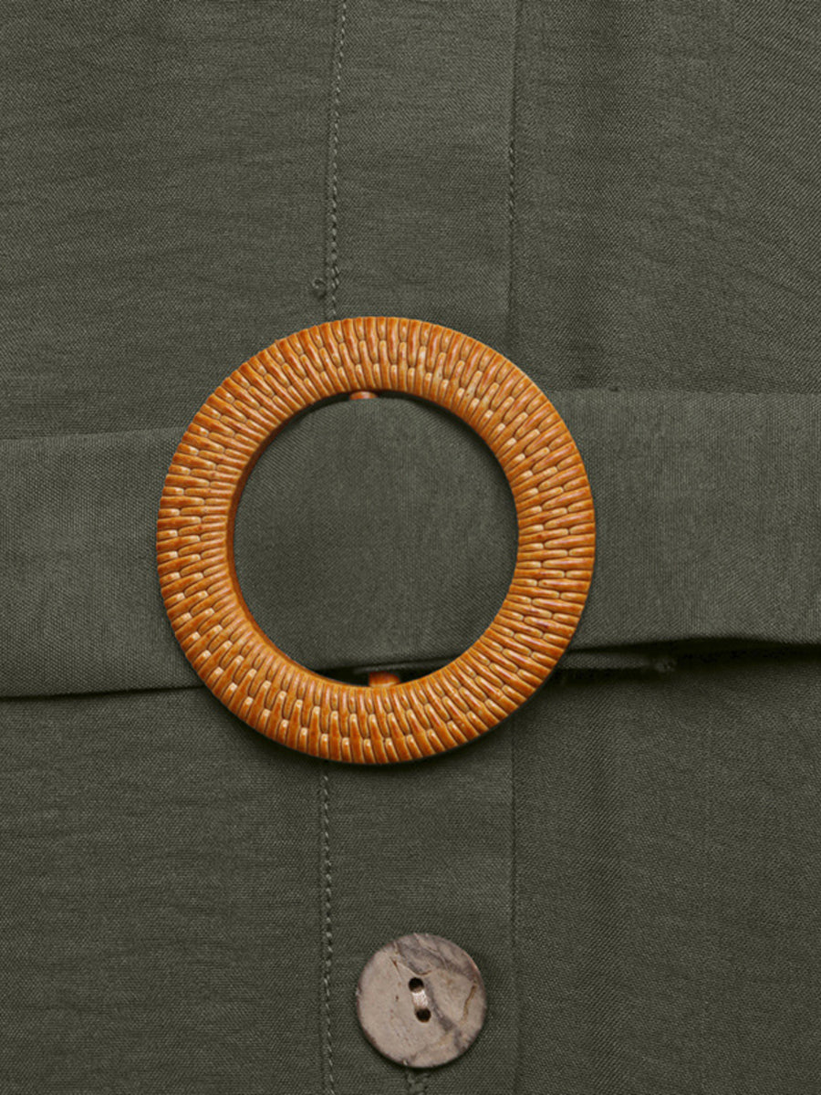 Close-up of a woven belt buckle on a green fabric background