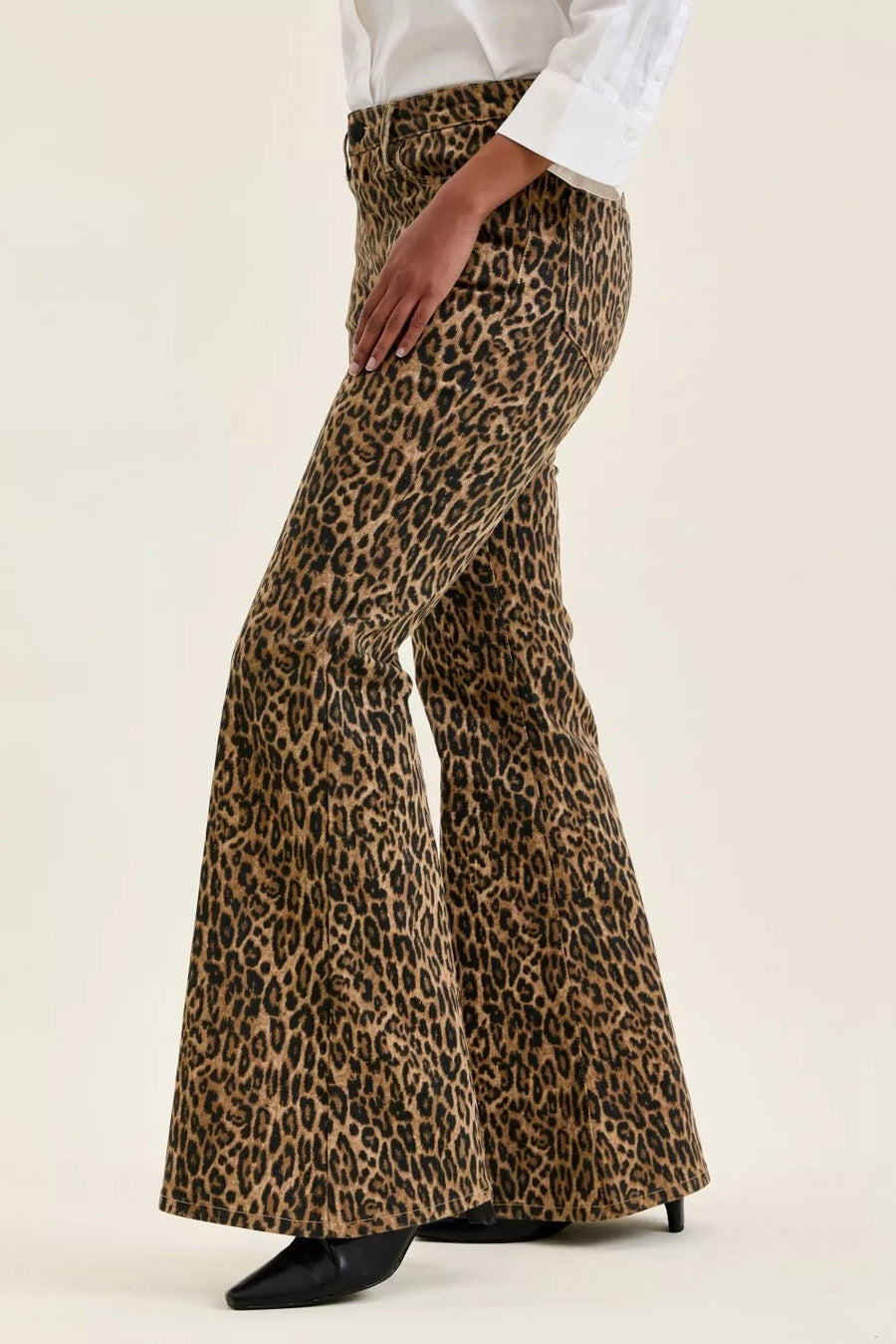 Leopard print flared pants worn with a white shirt on a beige background
