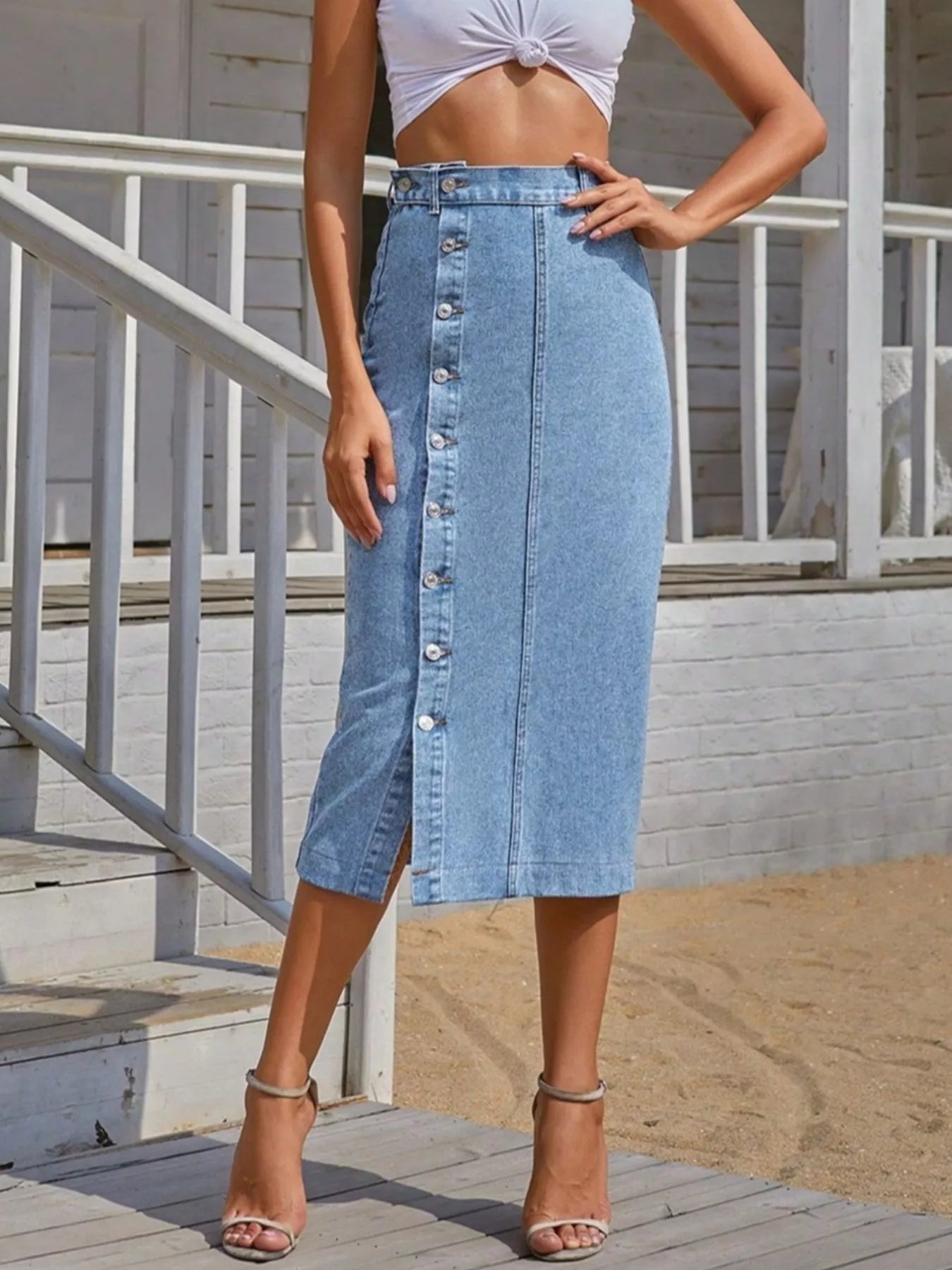 Woman wearing a denim skirt with button details outdoors.