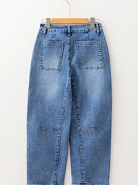 Blue jeans hanging on a wooden hanger against a white background